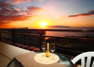a table with two wine glasses on a balcony with the sunset at Sunset Paradise in Adeje