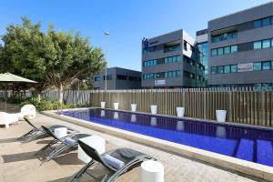 basen z krzesłami obok budynku w obiekcie Exe Puerto de Sagunto w mieście Puerto de Sagunto