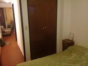 1 dormitorio con cama y puerta marrón en Depto San Bernardo céntrico sobre Costanera en San Bernardo