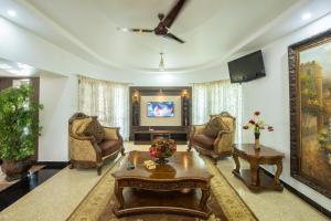 a living room with chairs and a table and a tv at Shoolin Resorts in Manipala