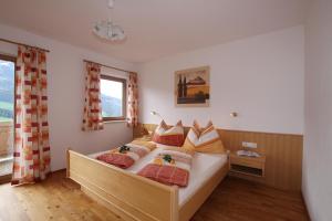 ein Schlafzimmer mit einem großen Bett mit orangefarbenen Kissen in der Unterkunft Bauernhof Hundbichl in Brixen im Thale