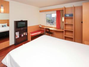 a hotel room with a bed and a desk and a tv at ibis Buenos Aires Congreso in Buenos Aires