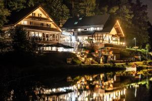 una casa illuminata di notte accanto a un lago di Hotel Reich am Ebnisee a Kaisersbach