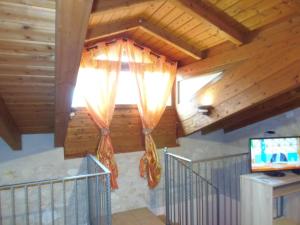 Habitación con techos de madera y una ventana con cortinas. en B & B AECOLIBRIUM, en Pastena