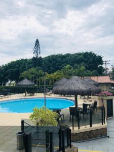 una piscina con mesas, sillas y sombrillas en AP em Floripa 2 quartos a 100m da praia - PRAIA BRAVA- NORTE DA ILHA, en Florianópolis