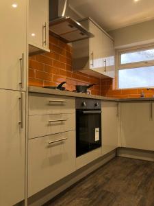 a kitchen with white cabinets and a stove top oven at 59 Wern Fawr Road in Swansea