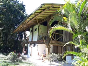 uma casa com um telhado de madeira e uma palmeira em Albergue de Montaña Talari em San Isidro