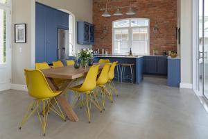ケープタウンにあるLe Vine Constantiaの木製テーブルと黄色い椅子付きのキッチン