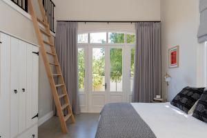 a bedroom with a bed with a ladder next to a window at Le Vine Constantia in Cape Town