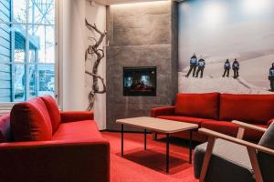 a living room with two red couches and a fireplace at Hotel Ylläsrinne in Ylläsjärvi