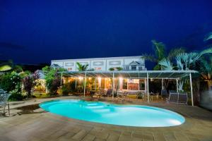 a swimming pool in front of a house at night at LA CIGALE in Foulpointe