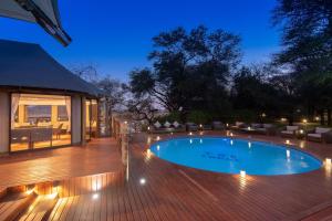 a swimming pool on a wooden deck at night at Tau Game Lodge in Madikwe Game Reserve