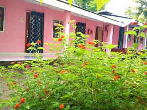 a pink house with flowers in front of it at Blue Bird Residency in Neil Island +6 photos