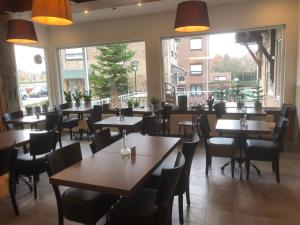 un ristorante con tavoli, sedie e ampie finestre di Mimosa Hotel a Valkenburg