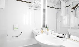 a white sink sitting under a mirror in a bathroom at Living Hotel Kanzler in Bonn