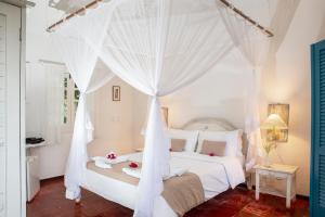 a bedroom with a white bed with a canopy at Pousada Casa Búzios in Búzios