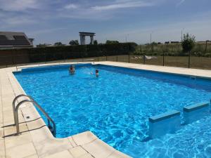 two people swimming in a large blue swimming pool at Holiday Home Nieuwendamme in Nieuwpoort