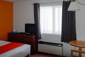 1 dormitorio con 1 cama, TV y ventana en Hotel Robin Hood en Grand Falls -Windsor