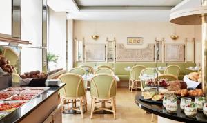 a kitchen filled with tables and chairs and a table with plates of food at Living Hotel Kanzler in Bonn