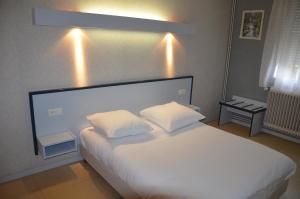 a bedroom with a large white bed with two pillows at HOTEL DU JURA in Louhans