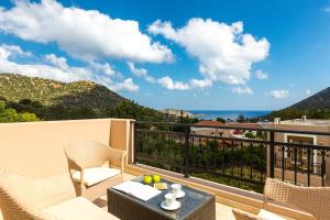 balcón con mesa, sillas y vistas al océano en Pantheon Villas & Suites en Balíon