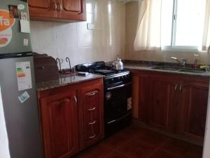 a kitchen with wooden cabinets and a black stove at La casita de Chany in Mina Clavero