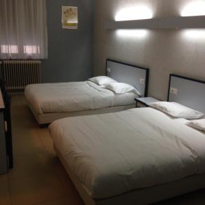 two beds in a hotel room with white sheets at HOTEL DU JURA in Louhans