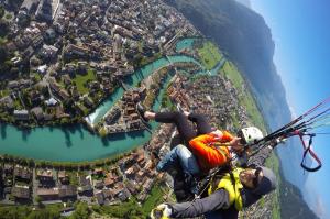 two people are hanging from a parachute over a city at City Center Holiday Apartment in Interlaken