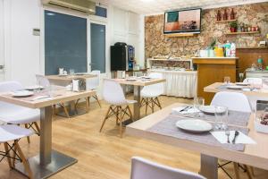 un restaurante con mesas de madera y sillas blancas en Hostal Menurka, en Ciutadella