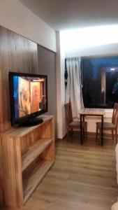 a living room with a flat screen tv and a table at Departamentos Patagonia in San Carlos de Bariloche