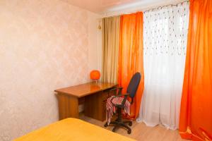 a bedroom with a desk and a chair next to a window at Apartment "Уют" in Ufa
