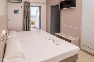 a bedroom with a large white bed and a window at Megim Hotel in Palaiochóra