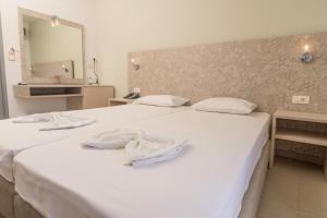 two white beds in a room with a mirror at Megim Hotel in Palaiochora