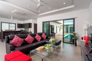 拉威海灘的住宿－Villa Nc10，客厅配有黑色沙发和红色枕头