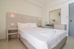 a bedroom with a large white bed and a mirror at Megim Hotel in Palaiochora