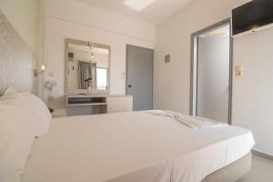 a white bedroom with a large bed and a mirror at Megim Hotel in Palaiochora