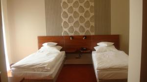 ein Hotelzimmer mit zwei Betten mit weißer Bettwäsche in der Unterkunft Hotel Rydzewski in Lyck