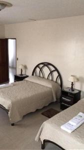 a bedroom with two beds and two tables with lamps at Hostal Jem in Cochabamba