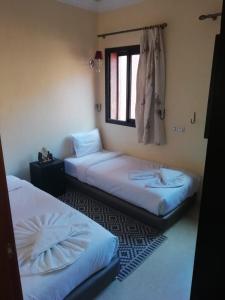Duas camas num quarto com uma janela em LINA APPARTEMENT em Marrakech