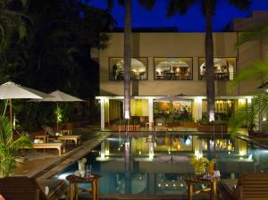 a resort pool with tables and umbrellas at night at Blue Diamond Pune IHCL SeleQtions in Pune