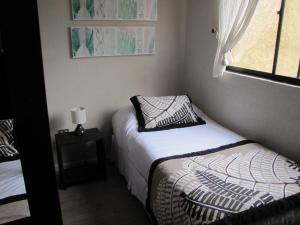 a small bedroom with two beds and a window at Apart Hotel Gran Pacifico in La Serena