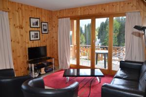 a living room with leather furniture and a balcony at Immeuble Les Sérandes in Les Collons