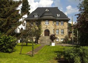 uma grande casa de pedra com um telhado preto em Rüters Parkhotel/Ferienwohnung em Willingen