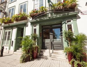 un bâtiment vert avec des plantes en pot sur la façade dans l'établissement Hotel le Priori, à Québec