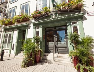 a green building with potted plants on the facade at Hotel le Priori in Quebec City