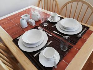einem Tisch mit weißen Tellern und Besteck in der Unterkunft Two Eggs in Kenmare