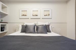Un dormitorio blanco con una cama grande con almohadas grises en ApartsNouBcn Fira Barcelona, en Hospitalet de Llobregat