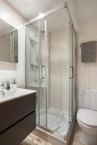 La salle de bains est pourvue d'une douche en verre et de toilettes. dans l'établissement ApartsNouBcn Fira Barcelona, à L'Hospitalet de Llobregat