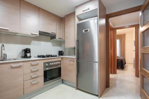La cuisine est équipée d'armoires en bois et d'un réfrigérateur en acier inoxydable. dans l'établissement ApartsNouBcn Fira Barcelona, à L'Hospitalet de Llobregat