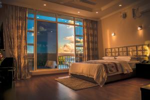 a bedroom with a bed and a large window at Abuharee Grand in Hithadhoo